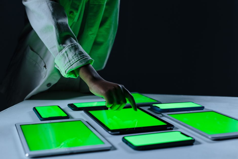 Ruka koja koristi više digitalnih tableta na zelenom ekranu